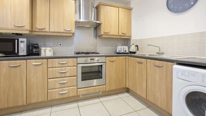 Een moderne keuken met houten kastjes, roestvrijstalen apparatuur, een inbouwoven, een magnetron, een broodrooster en een wasmachine.