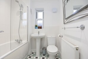 A bathroom with a bathtub, sink, toilet, and a window with a view of the outside. - Modern 4 Bed Home With Parking Close To Town (Cheltenham)