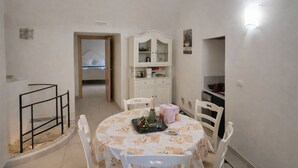 Un comedor con una mesa redonda, sillas, un armario y una escalera.