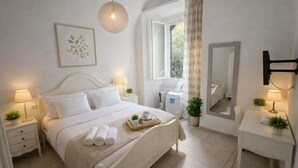 Un dormitorio ordenado con cama, mesitas de noche, un escritorio, un espejo y una ventana con cortinas.