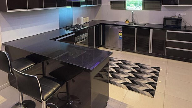 Una cocina moderna con armarios negros, una isla central y taburetes de bar.