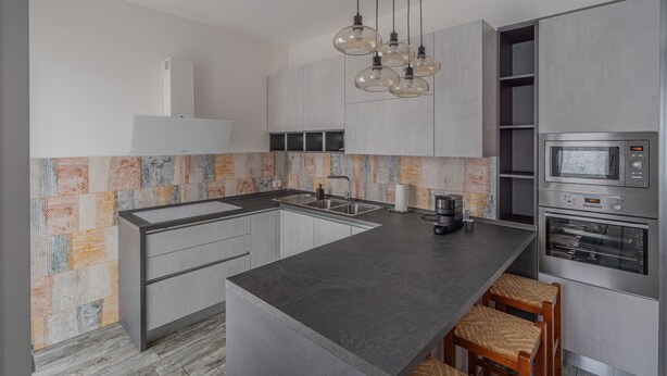 Uma cozinha moderna com ilha central, eletrodomésticos de aço inoxidável e painel de fundo trabalhado.