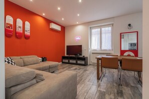 Ett modernt vardagsrum med en stor soffa, en tv och en matplats med stolar och ett bord.
