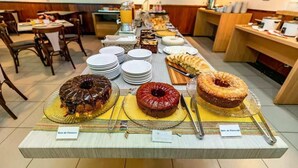 A buffet with various desserts and a wooden wall with fish decorations. - Ponta Negra Beach (Natal)