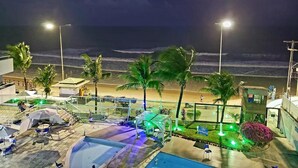 A beachfront hotel with a pool, outdoor seating, and palm trees. - Ponta Negra Beach (Natal)