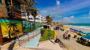 A beachside hotel with a staircase leading to a balcony, palm trees, and a view of the ocean. - Ponta Negra Beach (Natal)