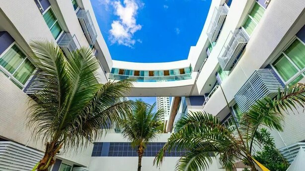 A modern building with a central atrium, multiple floors, and a clear blue sky. - Ponta Negra Beach (Natal)