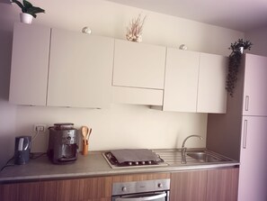 A kitchen with white cabinets, a coffee maker, a kettle, a toaster, and a sink. - Ocean Dream Beachhouse Apartment (Sal Rei)