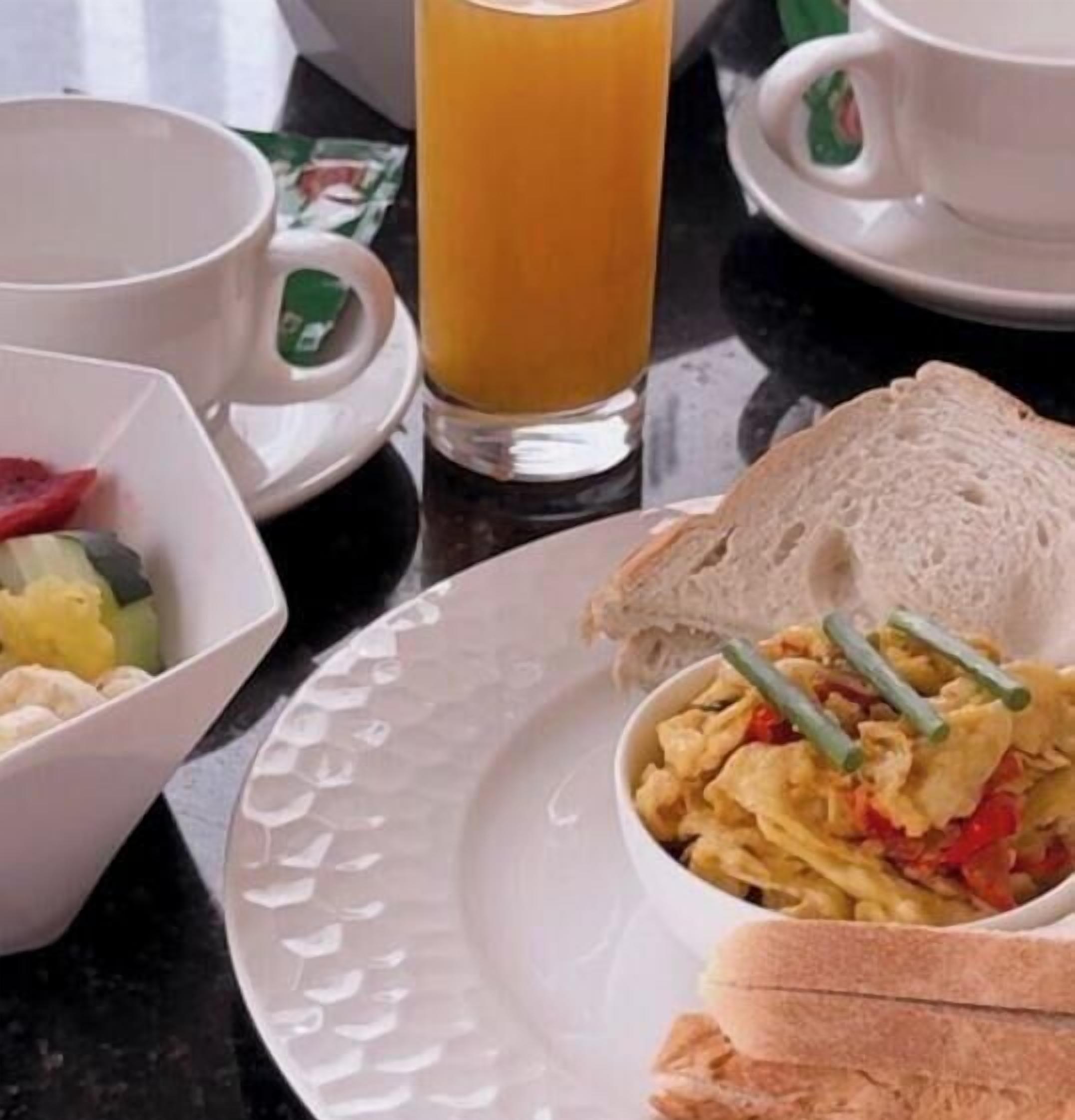 A breakfast setting with a plate of scrambled eggs, toast, and a glass of orange juice.