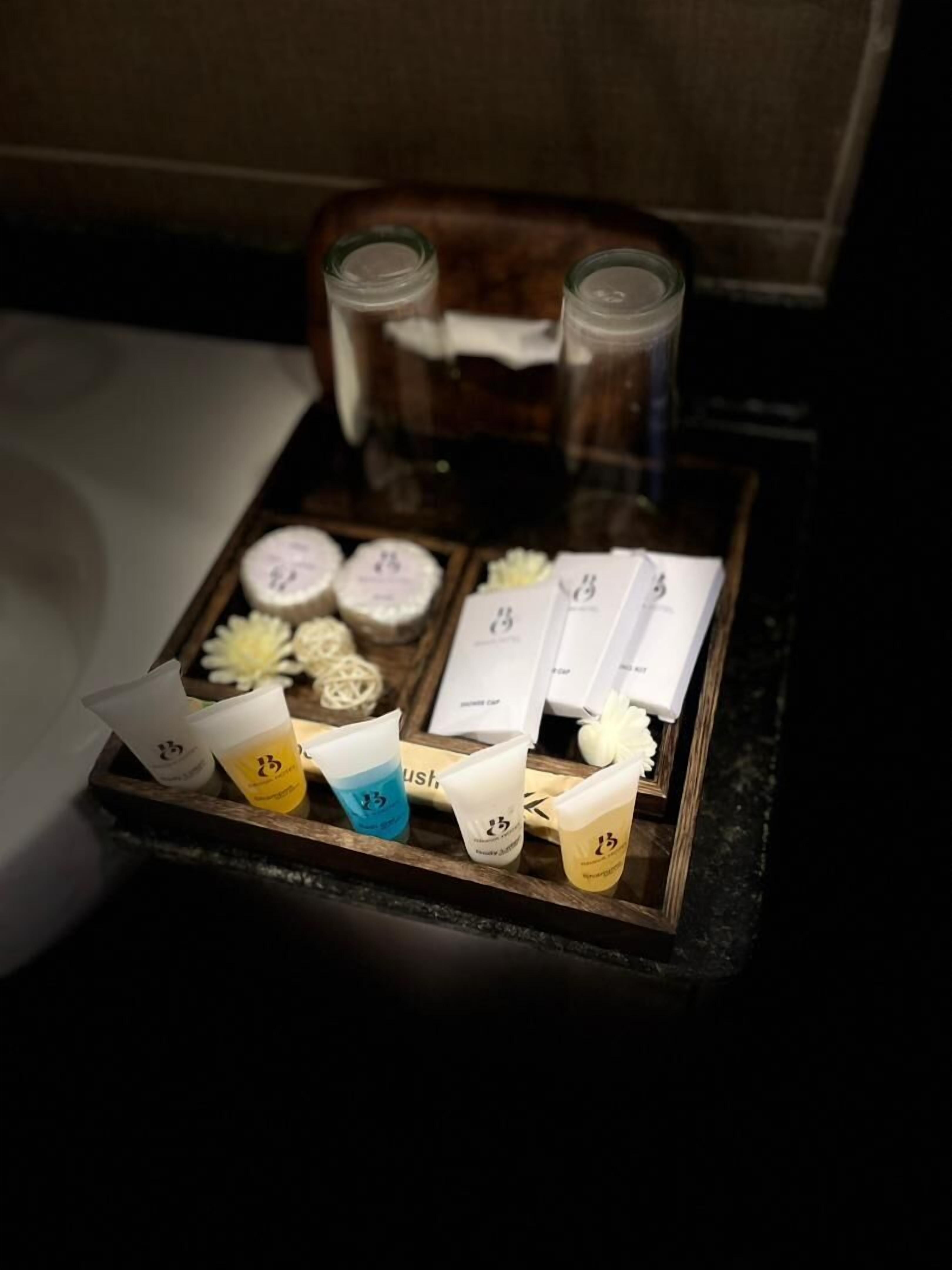 A tray with various toiletries and a small flower arrangement on a wooden surface.