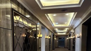 A hotel hallway with a central walkway, mirrored walls, and recessed ceiling lighting. - BRAVA HOTEL  (Ibadan)