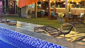 A pool area with lounge chairs, a covered seating area with string lights, and a bar. - BRAVA HOTEL  (Ibadan)