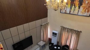 A modern living room with a sofa set, a TV, a chandelier, and a painting on the wall. - BRAVA HOTEL  (Ibadan)