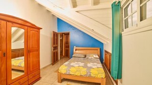 Un dormitorio con cama, armario y ventana con cortinas.