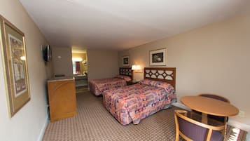 Una habitación de hotel con dos camas, un escritorio, una silla, un televisor y un cuadro en la pared.