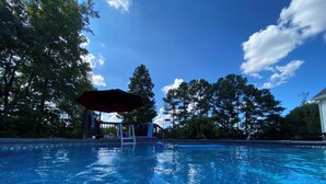 A clear swimming pool with a wooden deck, lounge chairs, and a covered area. - 3-bedroom home on quiet road with horse farms (Canton)