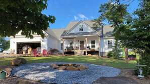 A two-story house with a front porch, a garage, and a landscaped yard with a fire pit. - 3-bedroom home on quiet road with horse farms (Canton)