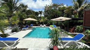 A pool area with lounge chairs and umbrellas, surrounded by tropical plants. - The Villa unit - The Agustin Guesthouse for Men, a beautiful & sexy resort oasis (Fort Lauderdale)