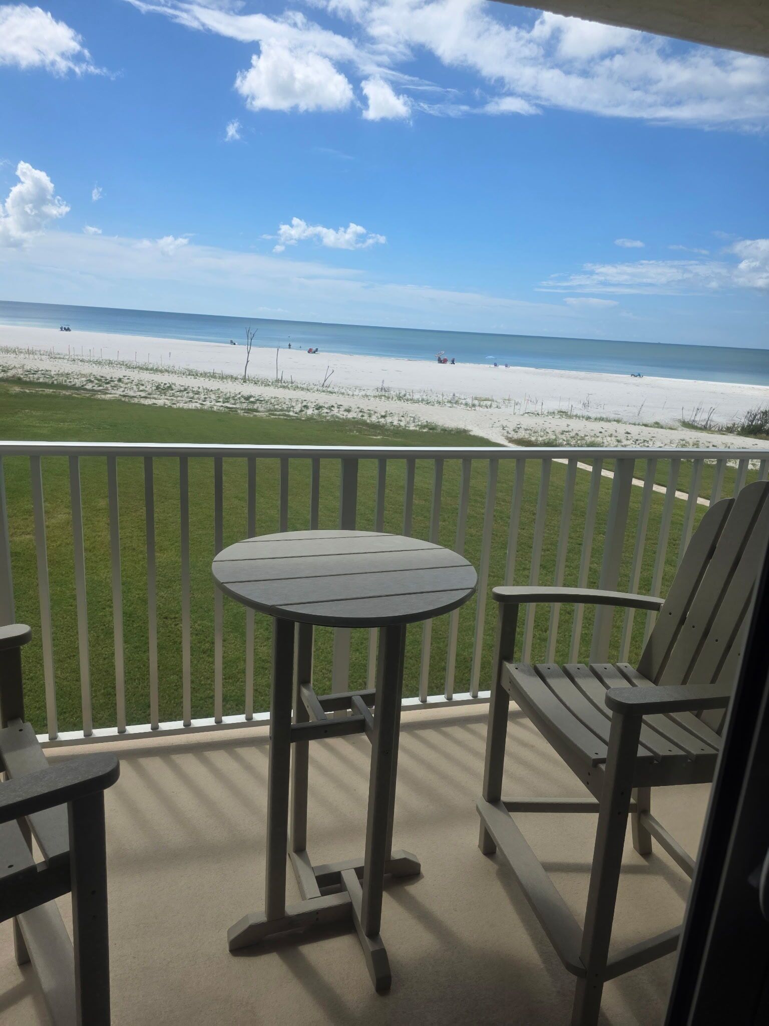 Un balcon donnant sur une plage, avec une table et deux chaises.