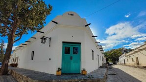 Un bâtiment blanc avec une porte turquoise, portant le numéro 1940, et un escalier en pierre menant à l’entrée.