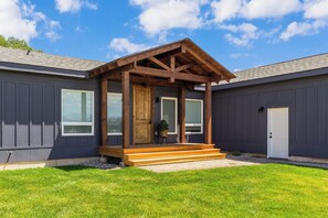 A modern house with a covered porch, large windows, and a well-maintained lawn.