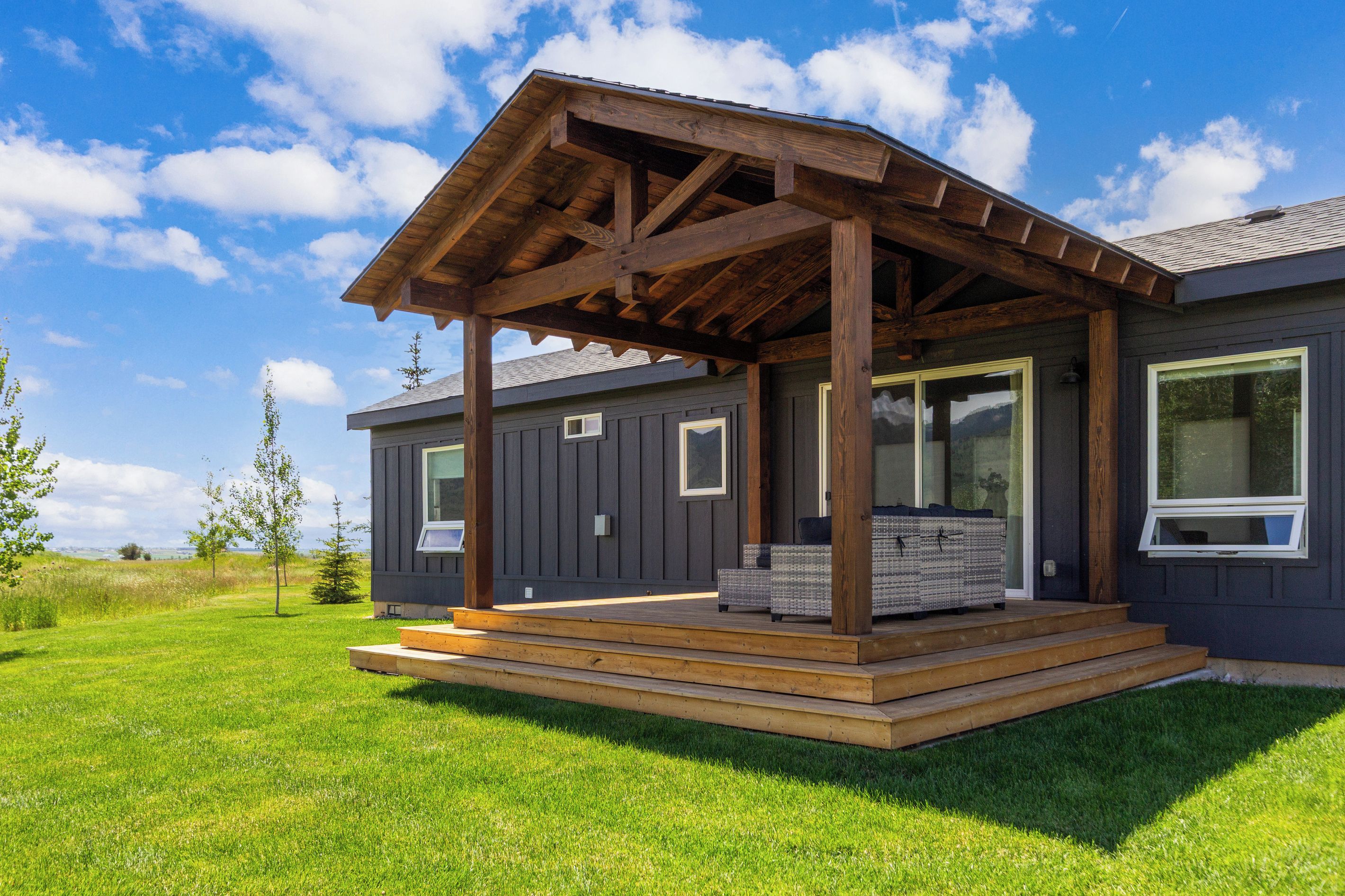 Une maison à deux étages avec une terrasse en bois et un porche couvert.