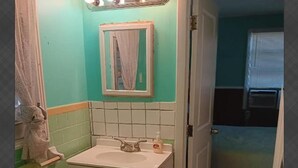 Un baño con lavamanos, espejo y toallero.
