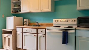 Una cocina con armarios blancos, cafetera, estufa y microondas.