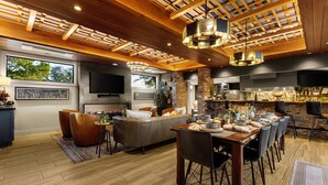 Un vaste espace de vie agrémenté d’un plafond en bois, d’une cheminée, d’un grand canapé et d’une table à manger pouvant accueillir six personnes.