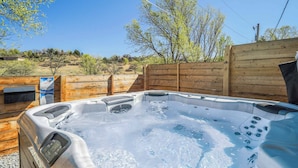 Een hottub in een open omgeving, met houten omheining en een heldere lucht.