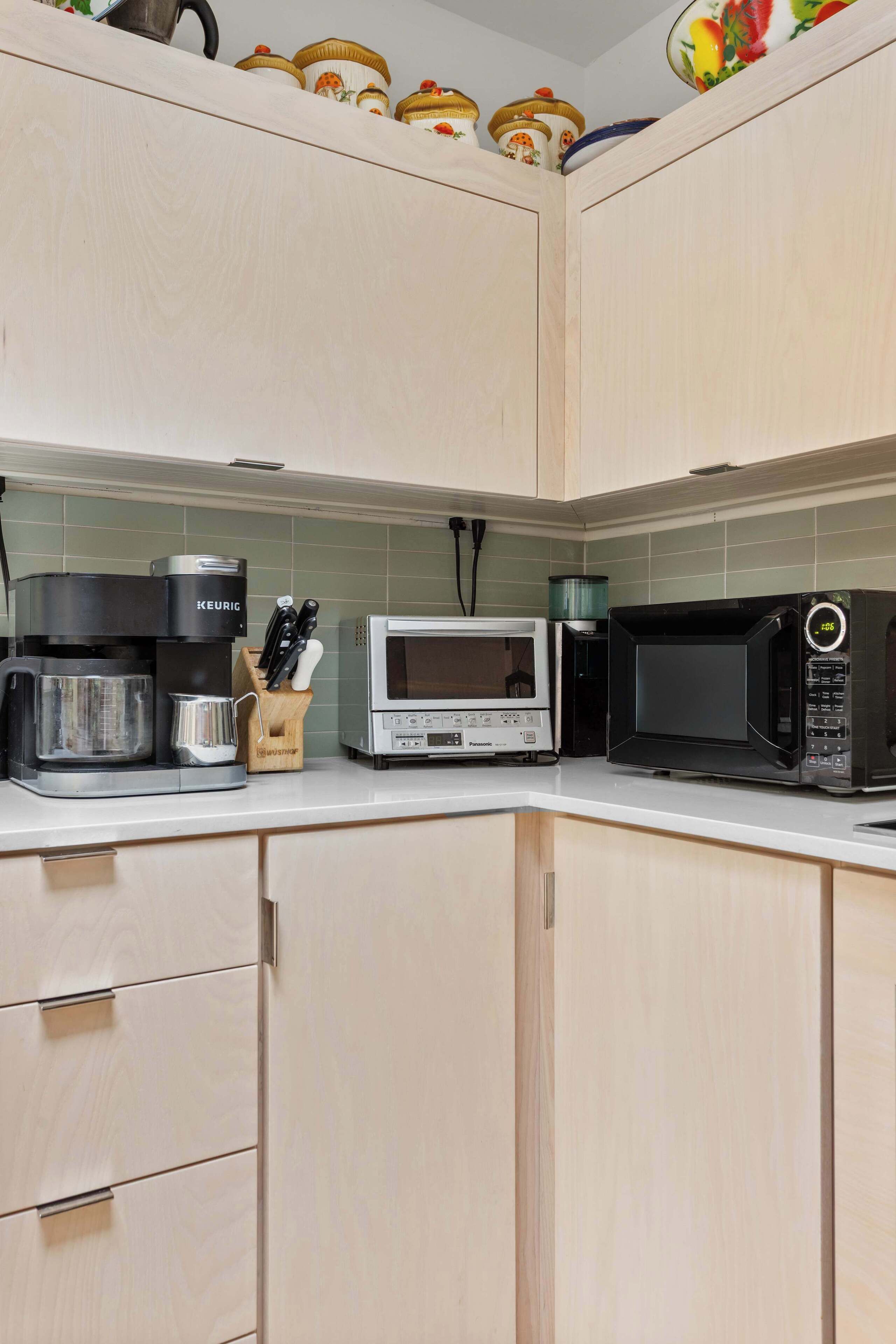 Eine Küche mit hellen Holzschränken, einer Kaffeemaschine, einer Mikrowelle und einem Toaster.