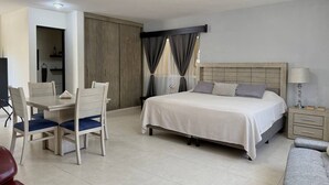 Ein Hotelzimmer mit einem Bett, einem Schreibtisch mit Stühlen, einem Fernseher und einem Nachttisch mit einer Lampe.