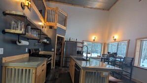 A modern kitchen with a central island, wooden cabinets, and a stainless steel refrigerator. - Barndominium in RACO, located very close to trails. (brimley)