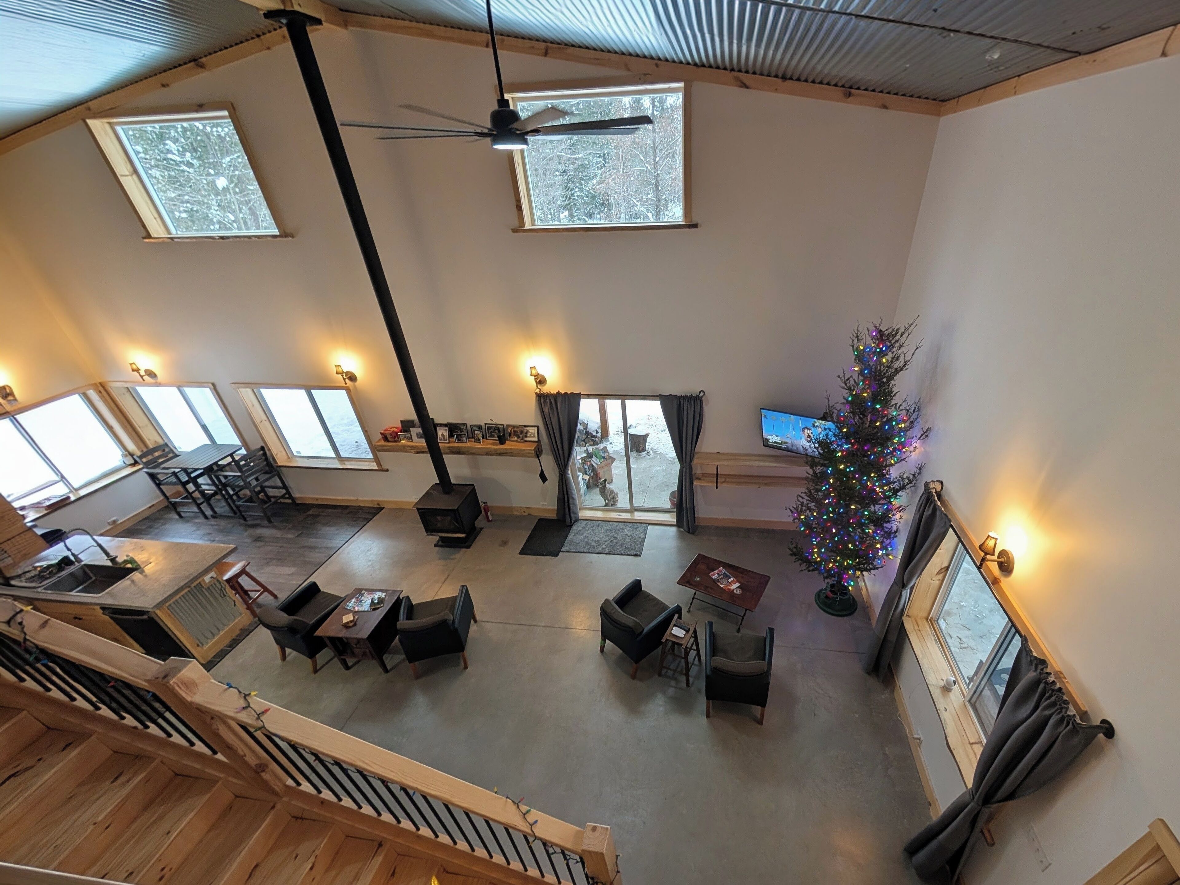 Un salón espacioso con techo alto, ventanas grandes, chimenea y un árbol de Navidad.
