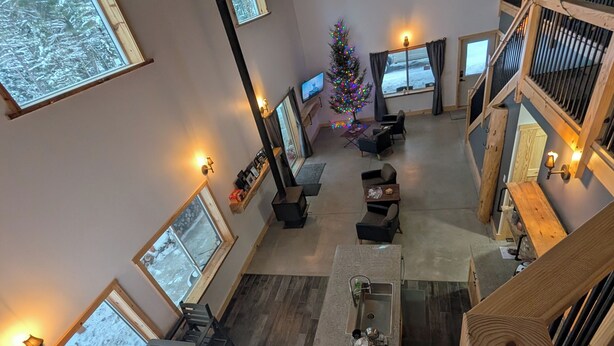 A spacious living area with a wooden staircase, a dining table, and a Christmas tree. - Barndominium in RACO, located very close to trails. (brimley)