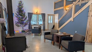 A cozy living room with a fireplace, comfortable seating, a Christmas tree, and a staircase. - Barndominium in RACO, located very close to trails. (brimley)