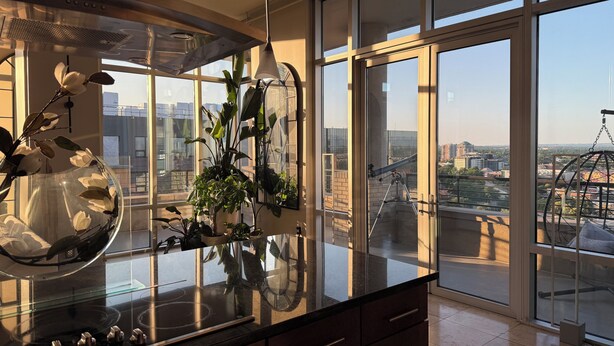 A modern kitchen with a large window, a glass-top stove, and a view of the cityscape. - COZY LUXURIOUS UPSCALE 1-BEDROOM PENTHOUSE DOWNTOWN DENVER! (Denver)