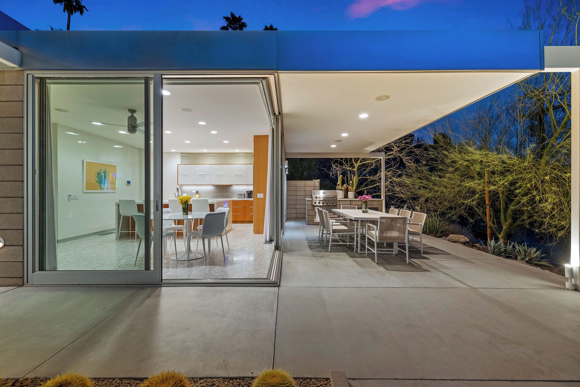 A modern house with a glass door entrance leading to a dining area and a kitchen.