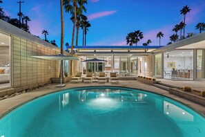 A modern pool area with lounge chairs and umbrellas, surrounded by palm trees and a clear sky. - Glass Haus - Desert Retreat with Epic Views! (Palm Springs)