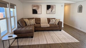 Een moderne woonkamer met een modulaire bank, een klein bijzettafeltje en een kamerkleed met dessin.