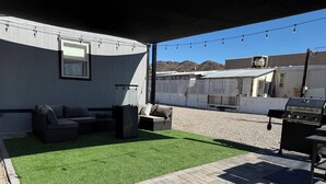 Een terras buiten met kunstgras, een barbecue en tuinmeubilair.