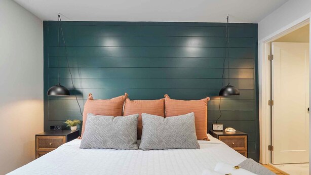 Ein Schlafzimmer mit einem Bett, zwei Nachttischen, einer Wanduhr und einer Tür.