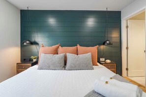 Una camera da letto con un letto, due comodini, una sveglia a parete e una porta.