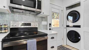 Een kleine keuken met een magnetron, oven en een ingebouwde wasmachine.