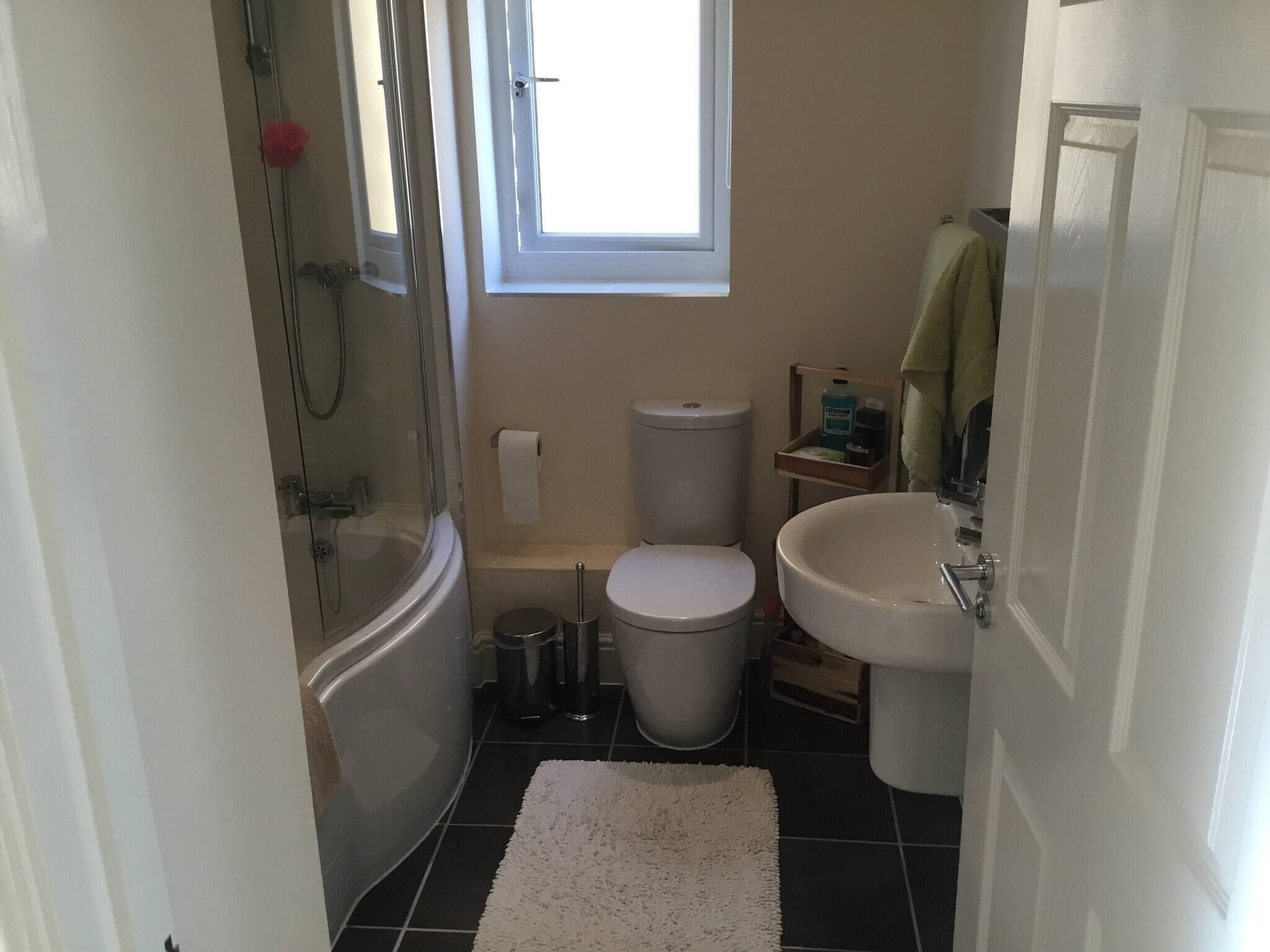 A compact bathroom with a shower, toilet, and sink.