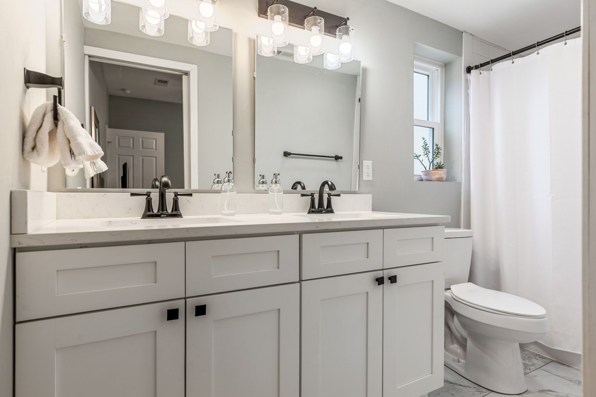 A modern bathroom with a double sink, a large mirror, and a shower curtain.