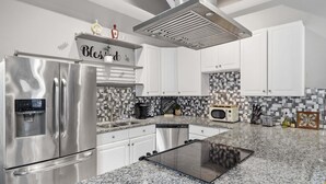 Uma cozinha moderna com eletrodomésticos de aço inoxidável, bancada de granito e painel de azulejos.