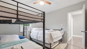 Quarto com beliche, ventilador de teto, porta e janela.
