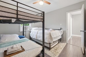A bunk bed room with a ceiling fan, a door, and a window.