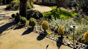 Una casa amb una entrada per cotxes, envoltada d'arbres i jardineria ben cuidada.